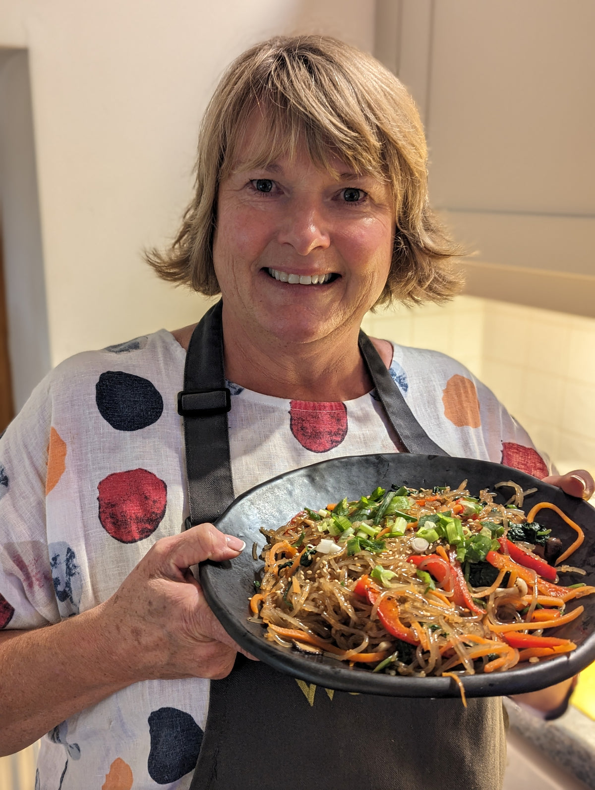 A guest proudly holding the japchae she made at the Korean Table class