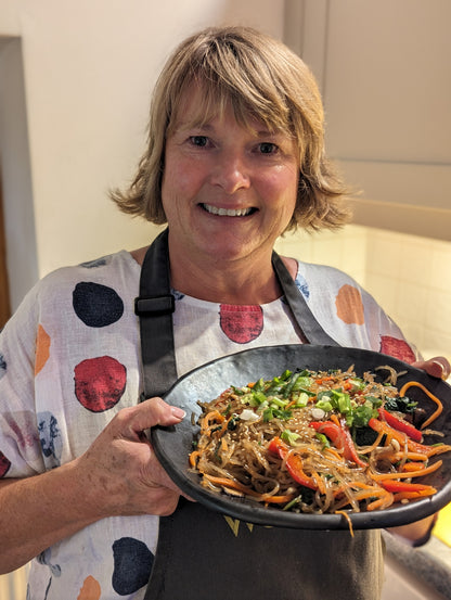A guest proudly holding the japchae she made at the Korean Table class